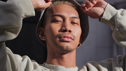 man in white sweater holding round mirror