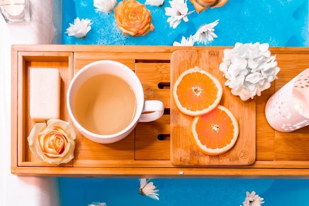 filled mug on brown wooden bathtub tray