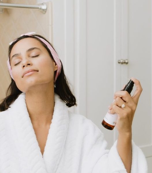 woman in white bathrobe holding smartphone