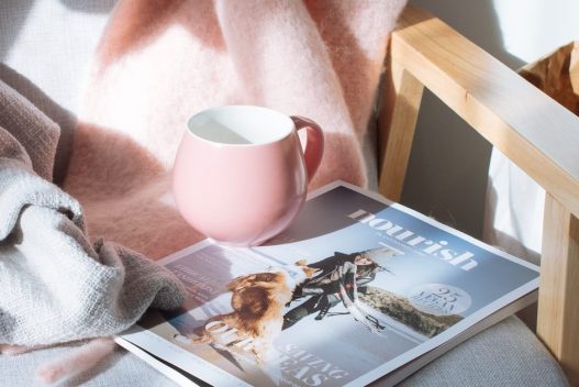 pink cup on top of magazine