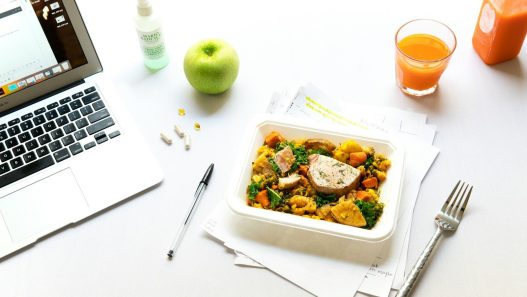 vegetables on plate beside fork and laptop